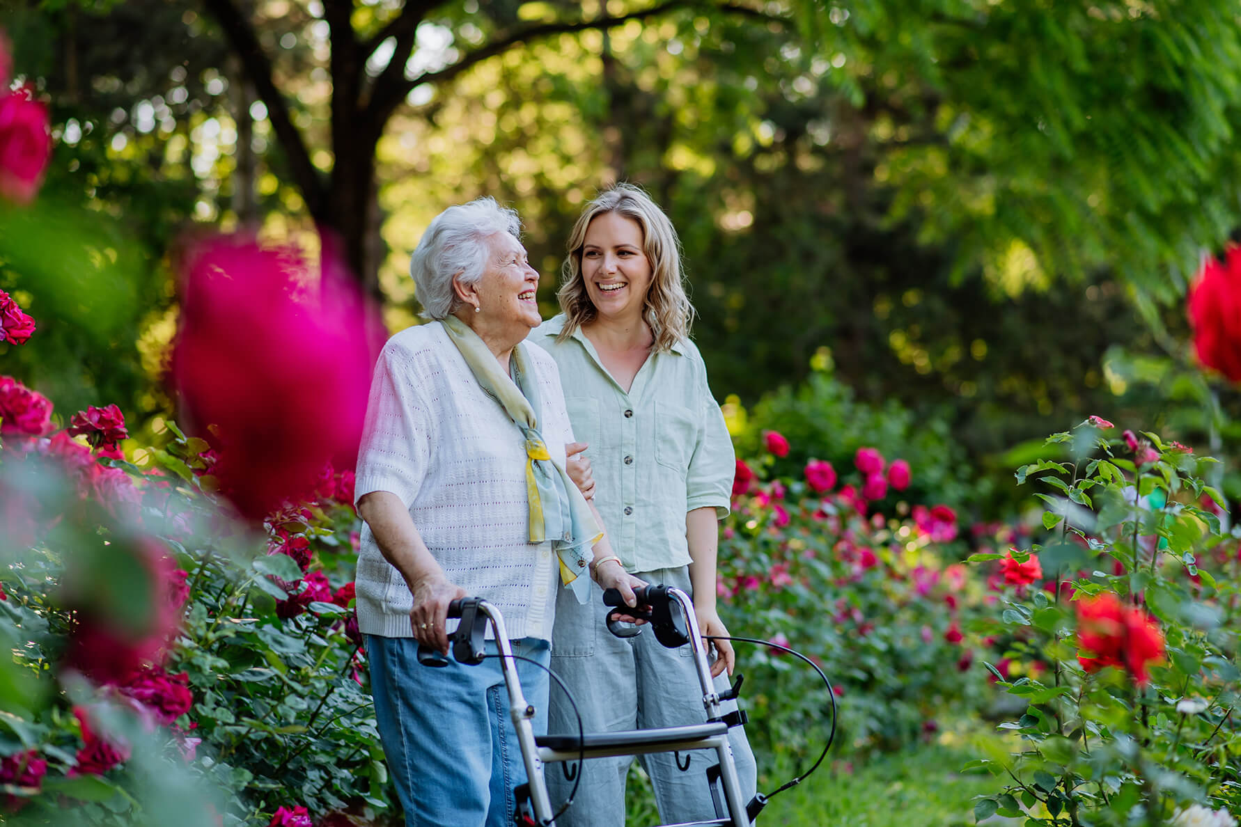 Elderly lady with carer walking in garden